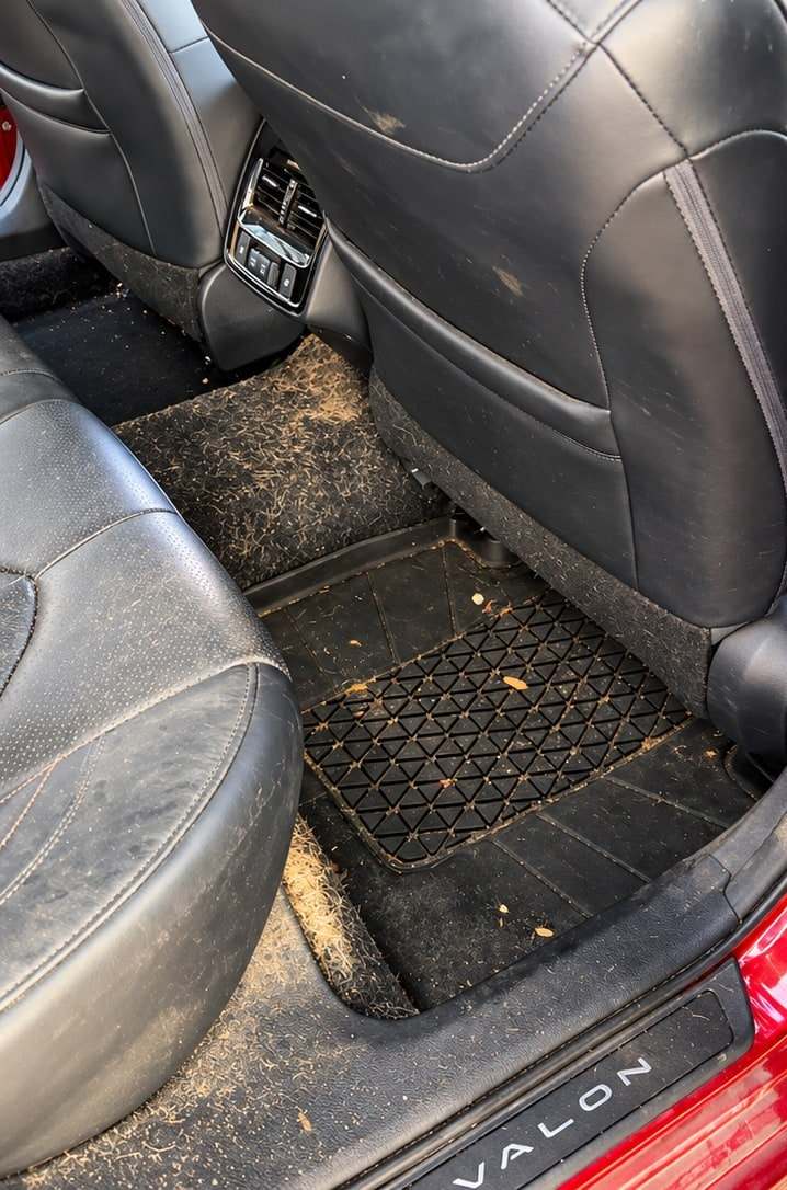Rear footwell and floor mat of a Toyota Avalon covered in dirt and debris