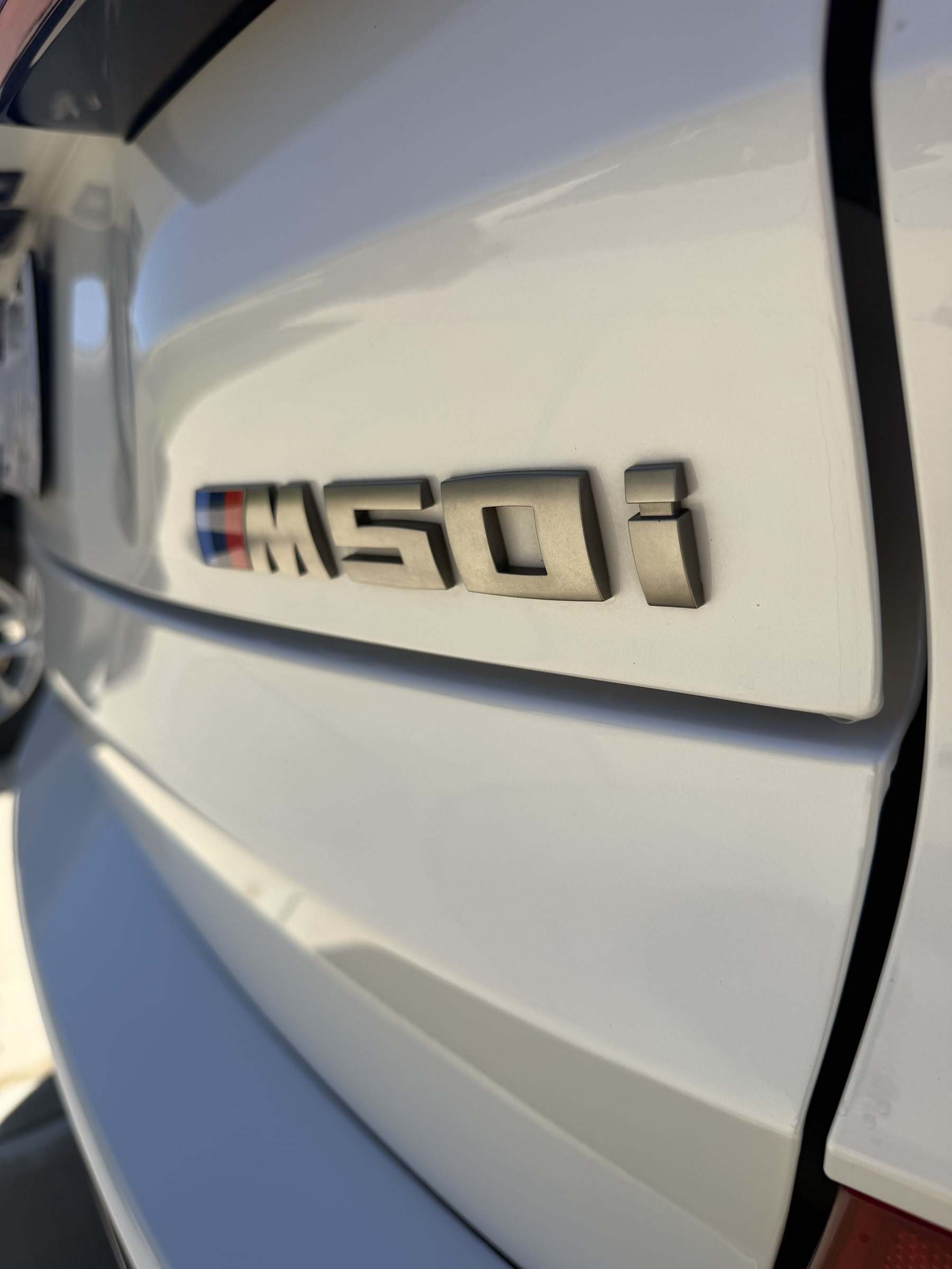 Close-up of a clean M50i badge on white BMW paint