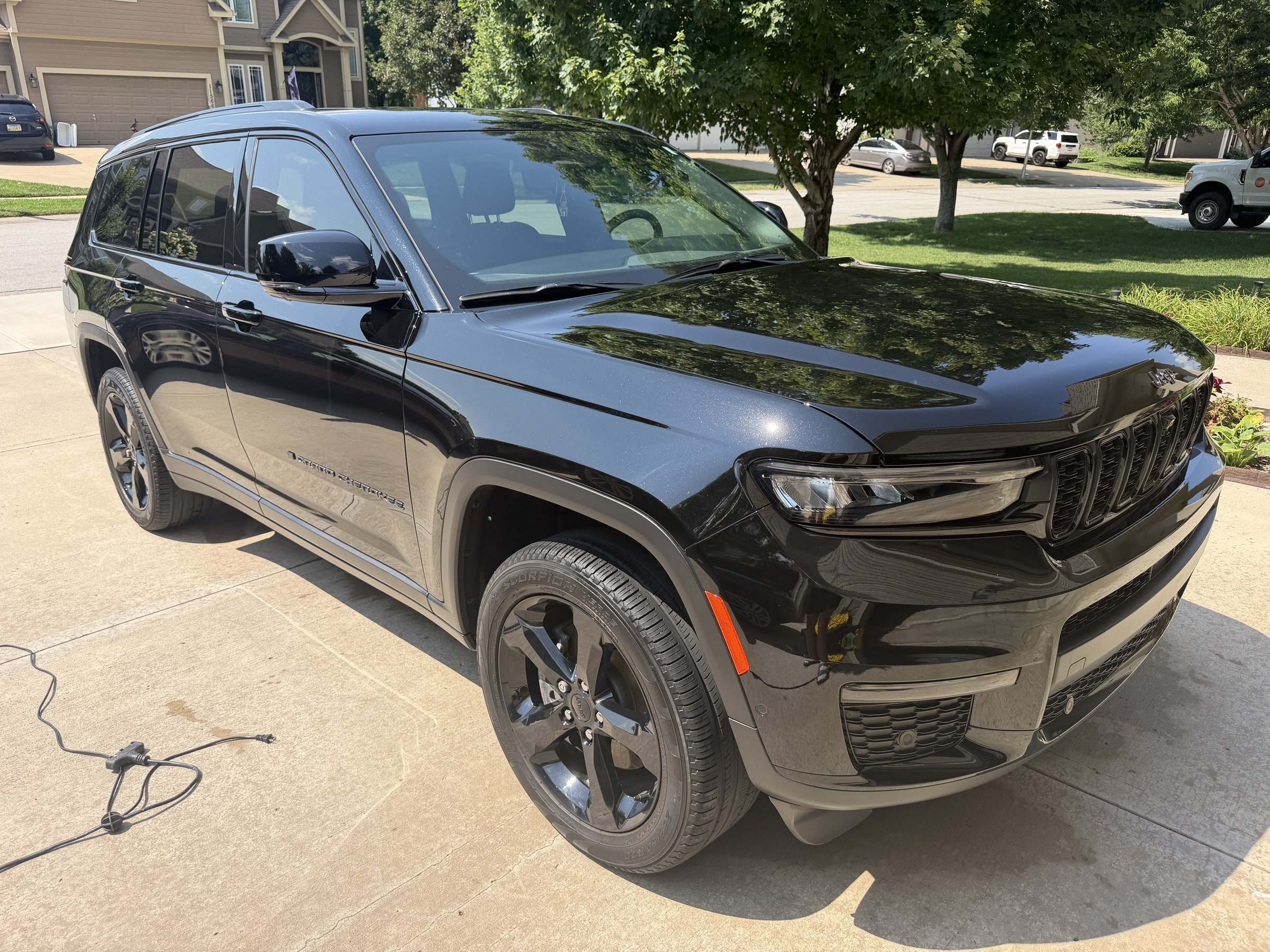 Glossy black Jeep Grand Cherokee on a residential driveway after a Takumi detail