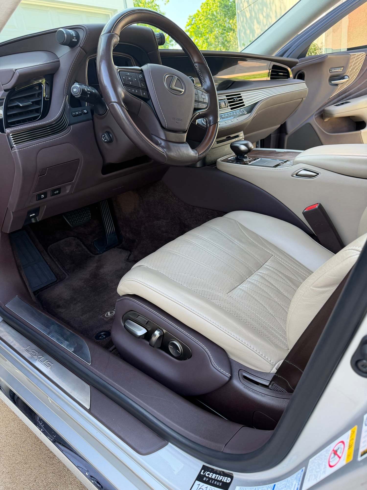 Cream leather driver seat and dark wood dash in a Lexus with the door open