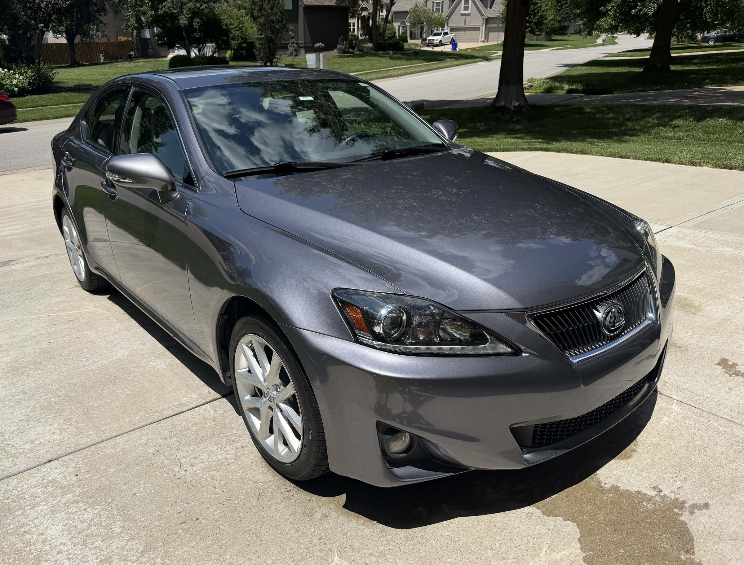 Gray Lexus IS sedan on a concrete driveway after a Takumi detail