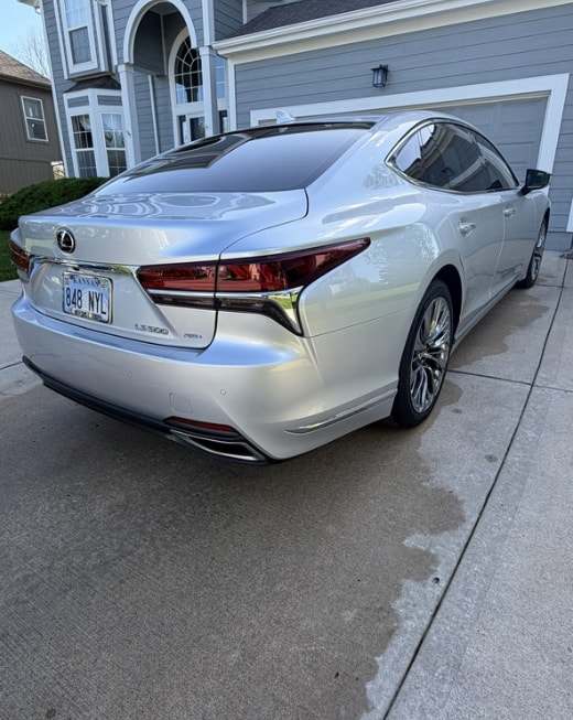 Rear three-quarter view of a silver Lexus LS 500 on a wet driveway