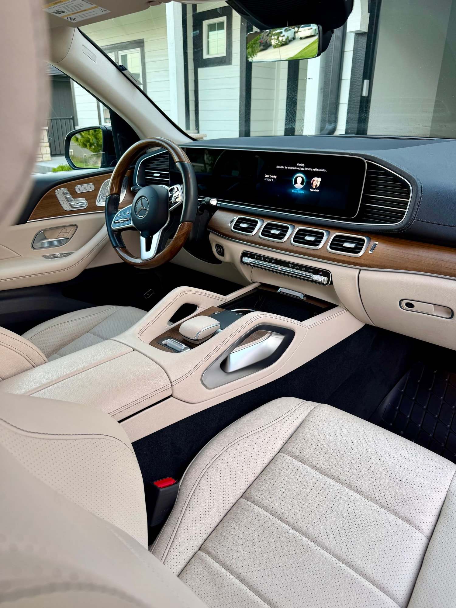 Cream leather front seat, wood trim, and digital dash inside a Mercedes-Benz