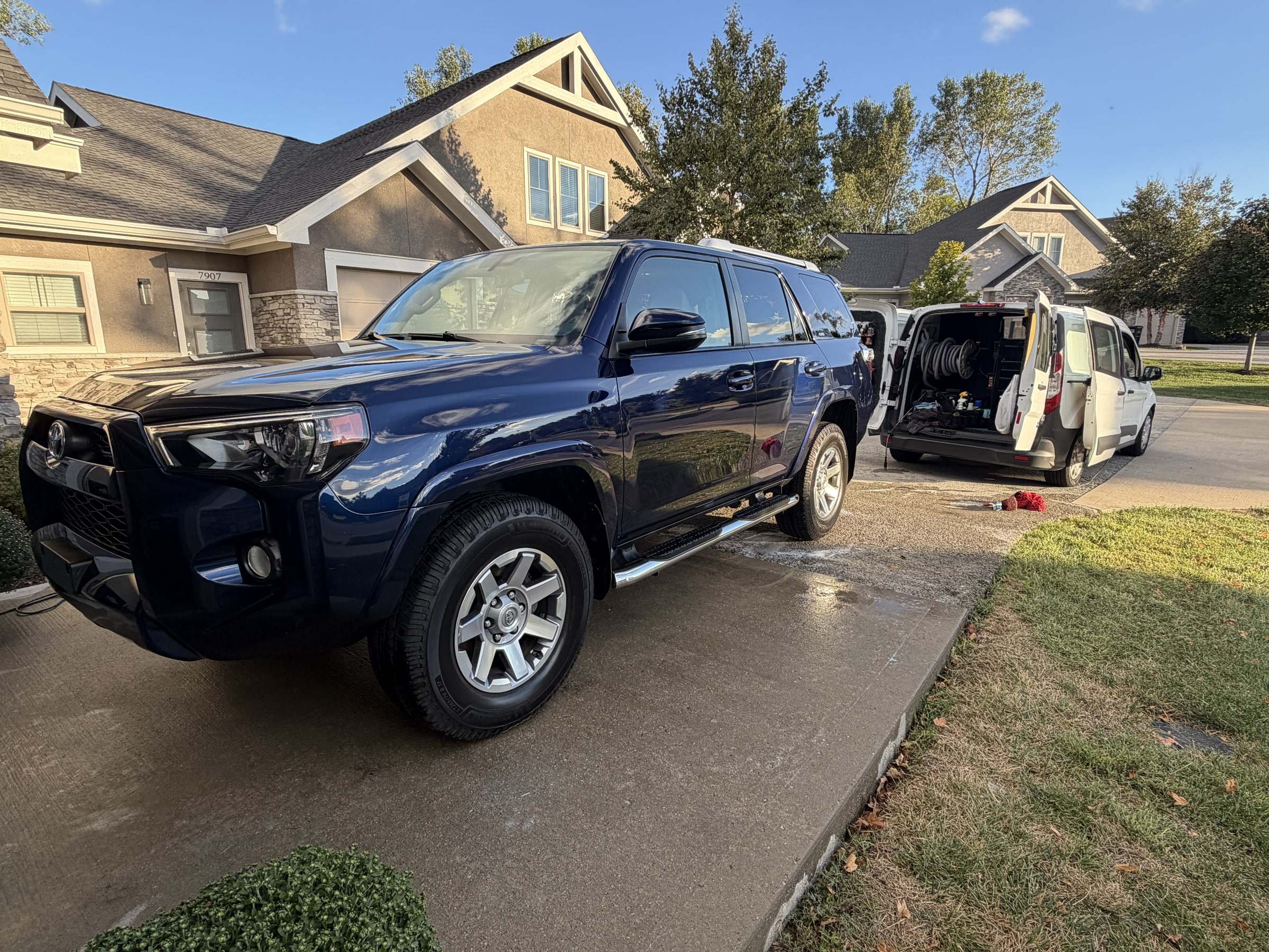 Blue Toyota 4Runner on a residential driveway, with the mobile detailing van parked in the background