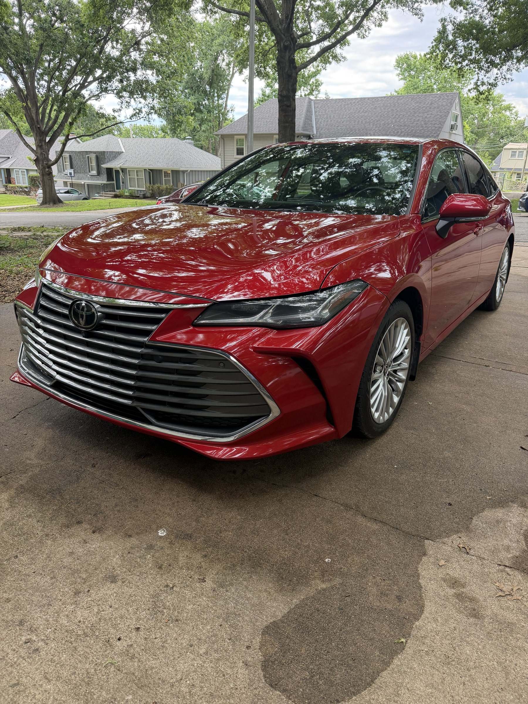 Glossy red Toyota Avalon on a tree-lined residential driveway