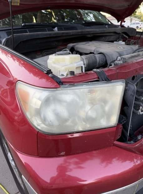 Red Toyota Tundra with a hazy headlight, hood open, before the detail